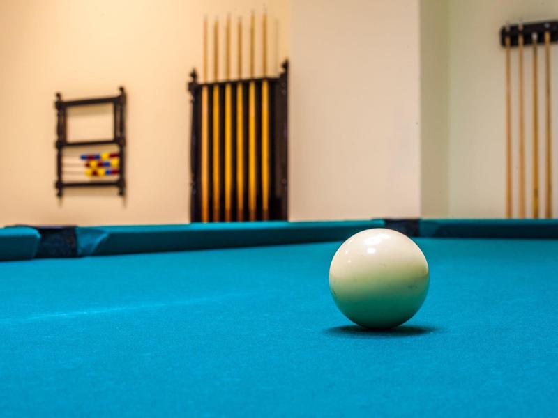 Primo piano di una palla bianca da biliardo su un tavolo da biliardo blu con stecche sullo sfondo