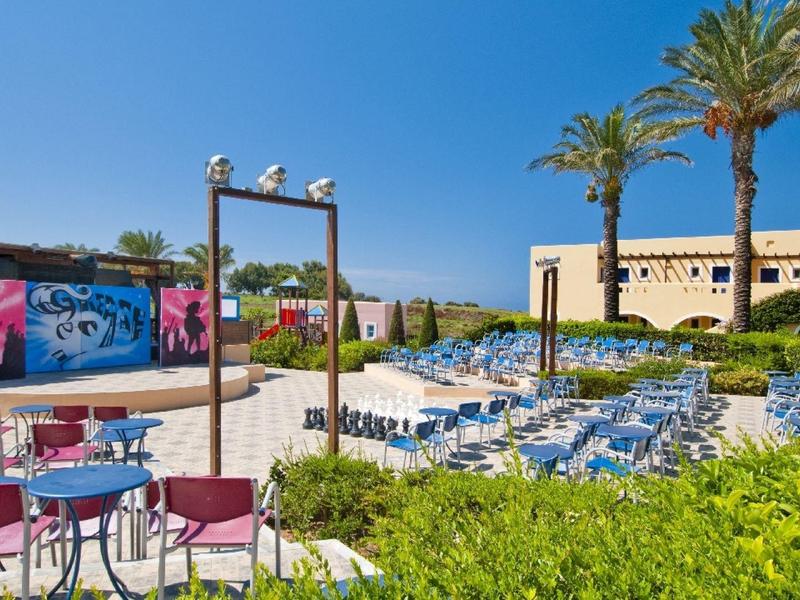 Terrazza dell'hotel con posti a sedere, lettini, palme e cielo azzurro.