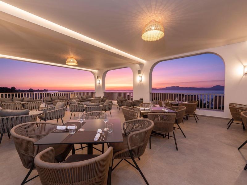 Terrazza dell'hotel con aree salotto e vista al tramonto sul mare.