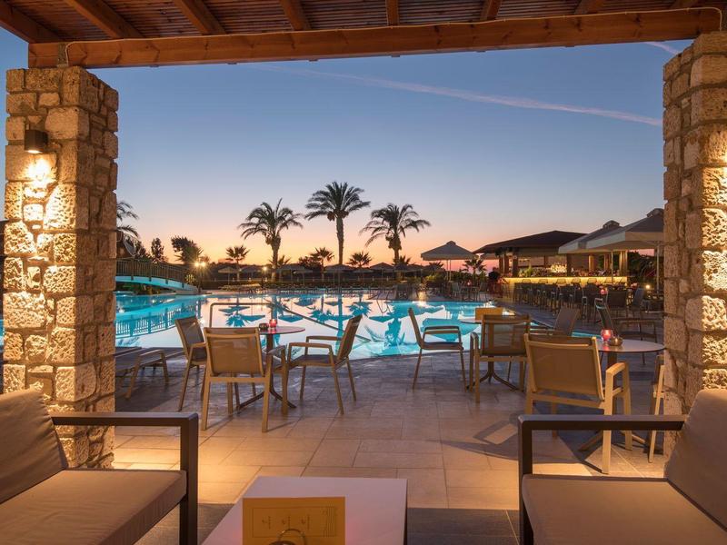 Vista serale di una piscina illuminata con aree salotto in un hotel.