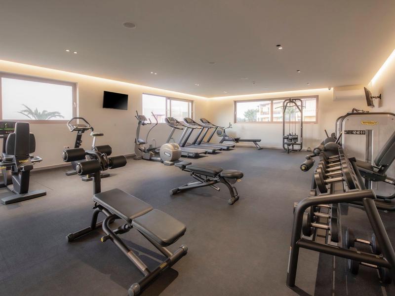 Palestra luminosa con varie attrezzature da allenamento e grandi finestre