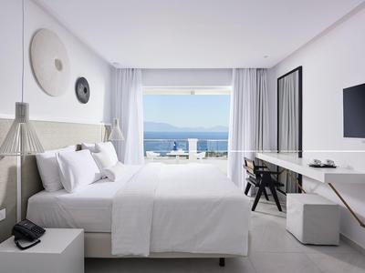 Camera d'hotel moderna con letto matrimoniale, scrivania e vista mare attraverso grandi finestre