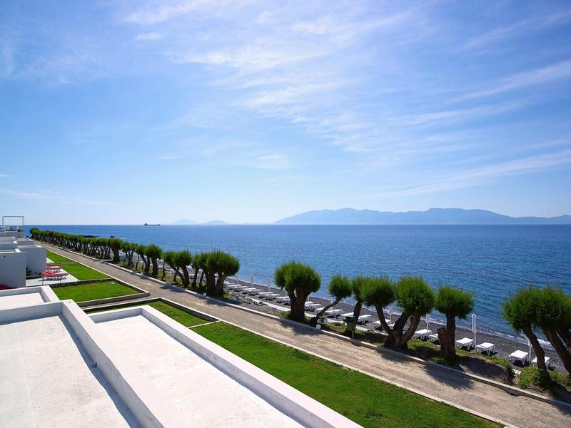 Vista su una passeggiata con piccoli alberi lungo l'acqua sotto un cielo azzurro limpido.
