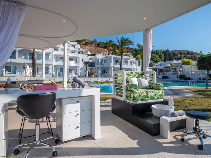 Spazio di lavoro moderno all'aperto con sedia, divano e vista sulla piscina e gli edifici dell'hotel.