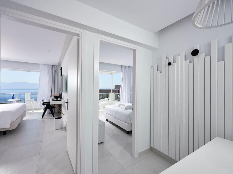 Corridoio di un hotel moderno con vista su due camere doppie e sul mare sullo sfondo.