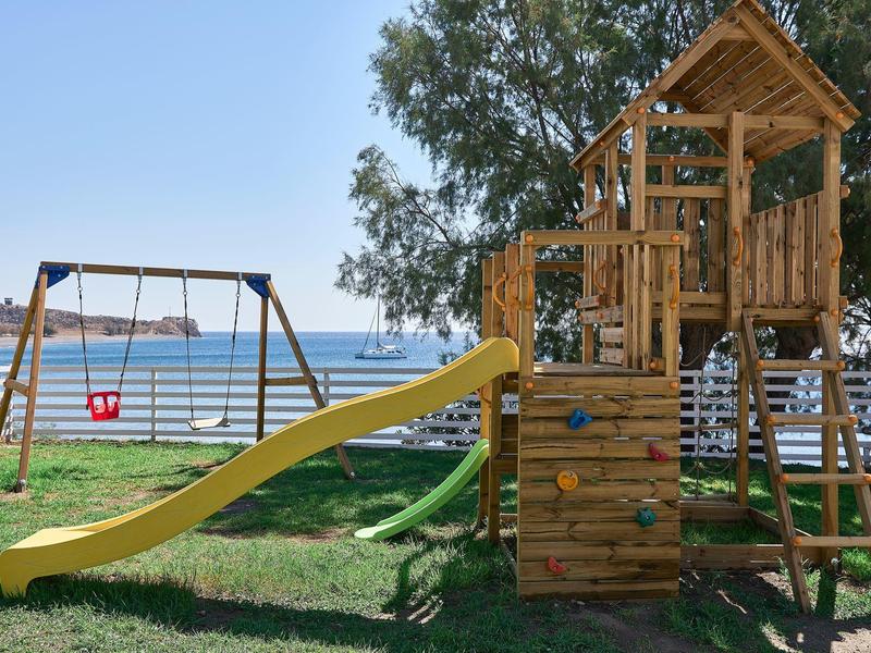 Area giochi per bambini con scivolo, struttura per arrampicata e altalena vicino a un lago