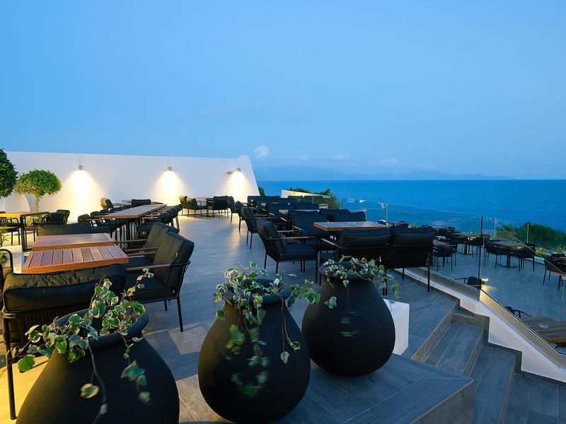 Terrazza panoramica con sedute, grandi vasi e vista sul mare al crepuscolo.