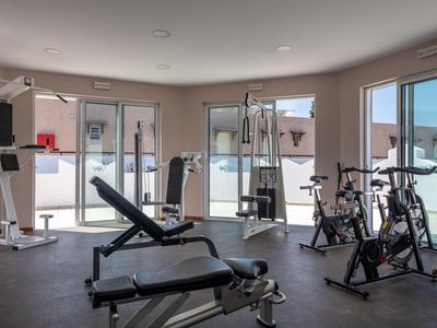 Palestra moderna con attrezzature per l'allenamento e grandi finestre con vista esterna.