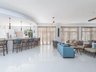 Area lounge hotel moderna e luminosa con divani blu e sgabelli in legno