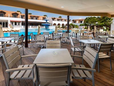 Area esterna coperta con tavoli e sedie vicino alla piscina dell'hotel.