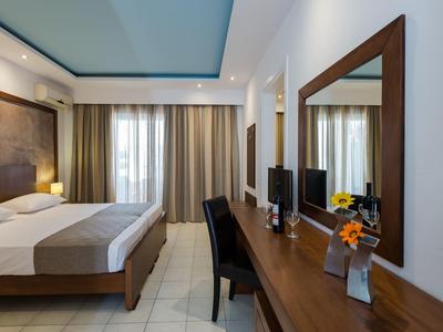 Camera d'hotel moderna con letto matrimoniale, scrivania, specchio e tende alla finestra.