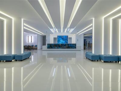 Moderna hall d'hotel con pavimento lucido, sedute blu e pareti illuminate.