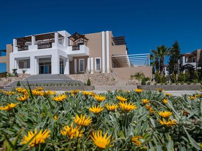 Edificio moderno dell'hotel bianco con aiuola di fiori in primo piano sotto cielo azzurro
