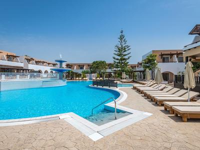 Grande piscina dell'hotel con lettini e cielo azzurro terso sullo sfondo.