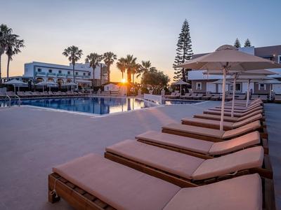 Sonnenuntergang an einem Hotelpool mit Liegestühlen und Sonnenschirmen in einer entspannten Atmosphäre.