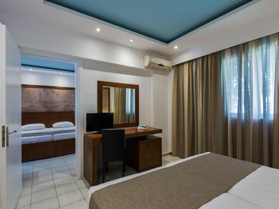 Camera d'hotel con vista sulla camera da letto, scrivania, sedia e tende alla finestra.