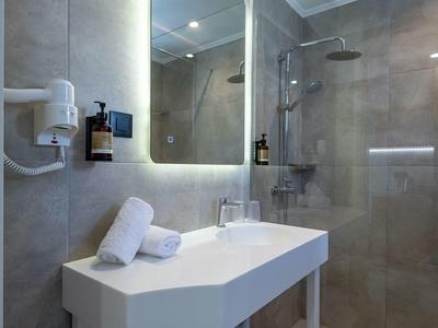 Bagno moderno con specchio illuminato, lavabo bianco e asciugamani.