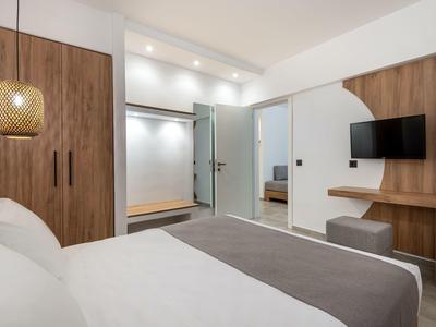 Camera da letto con letto matrimoniale, mobili in legno, TV a parete e cabina armadio con porta in vetro