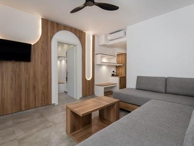 Zona giorno moderna con divano ad angolo grigio, tavolo in legno, TV a parete e illuminazione d'ambiente.