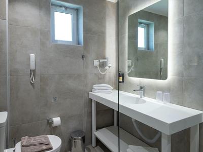Bagno moderno d'hotel con lavabo, specchio illuminato e WC.