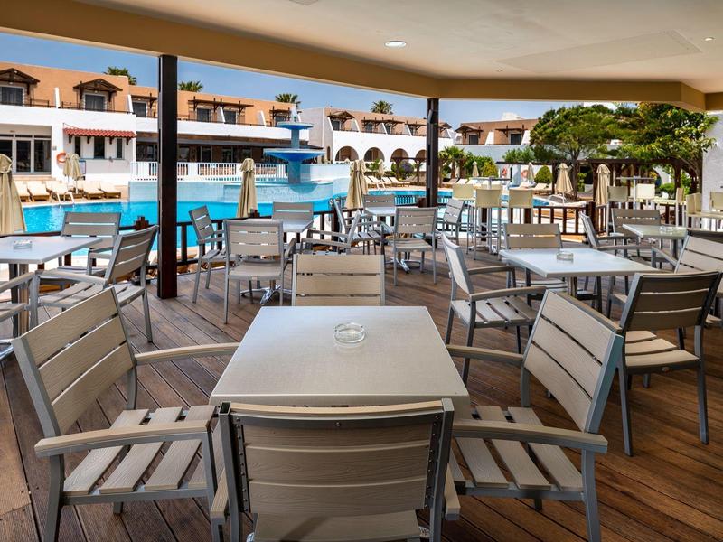 Area esterna coperta con tavoli e sedie vicino alla piscina dell'hotel.