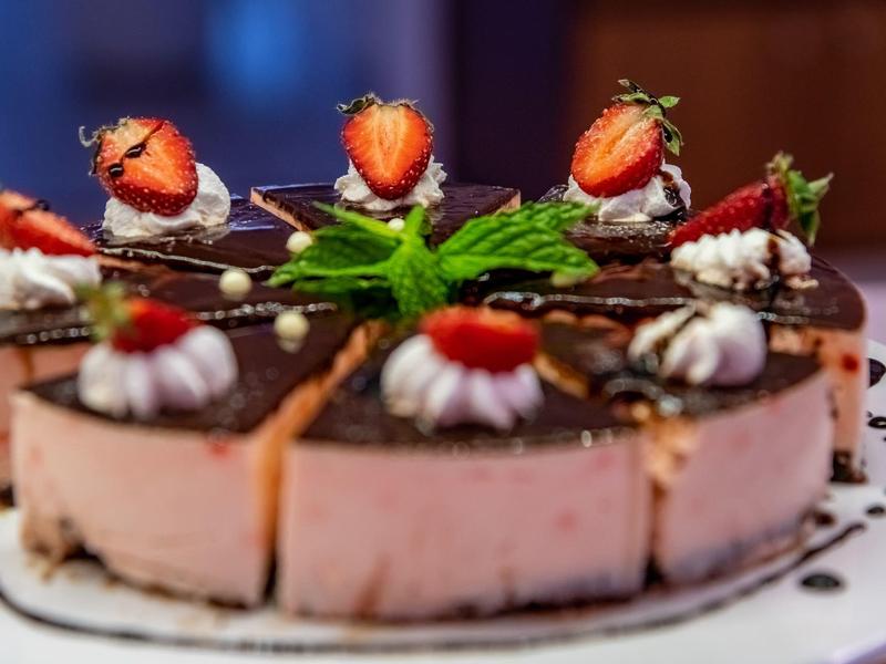 Torta al cioccolato e fragole decorata con panna e foglie di menta su un piatto bianco.