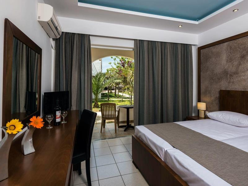 Camera d'hotel con letto matrimoniale, scrivania, sedia e vista sulla terrazza con giardino