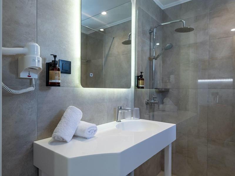 Bagno moderno con specchio illuminato, lavabo bianco e asciugamani.