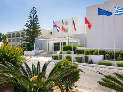 Edifici dell'hotel bianchi con diverse bandiere sotto un cielo azzurro e piante verdi in primo piano