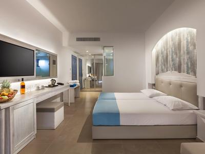 Modernes Hotelzimmer mit Doppelbett, TV, Schreibtisch und stilvoller Beleuchtung.