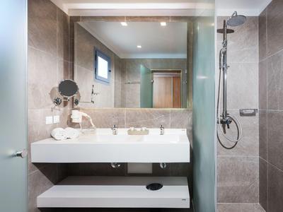 Modernes Hotelbadezimmer mit Waschbecken, großem Spiegel und Regenwalddusche.