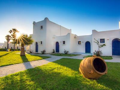 Tramonto su hotel bianco con cielo blu, prato verde e anfora mediterranea.