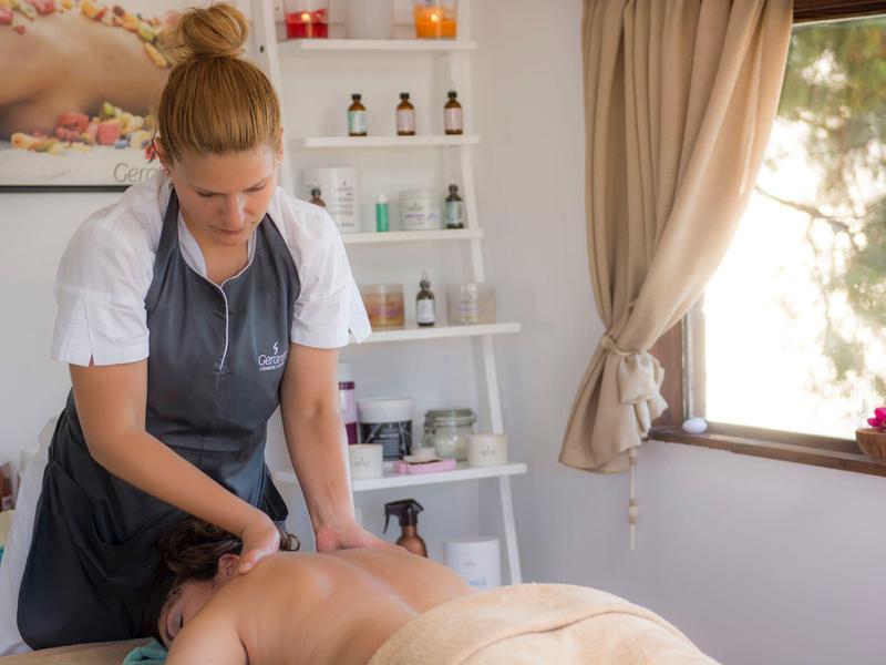 Frau erhält Rückenmassage in einem hellen, ruhigen Wellnessraum mit Blick nach draußen.
