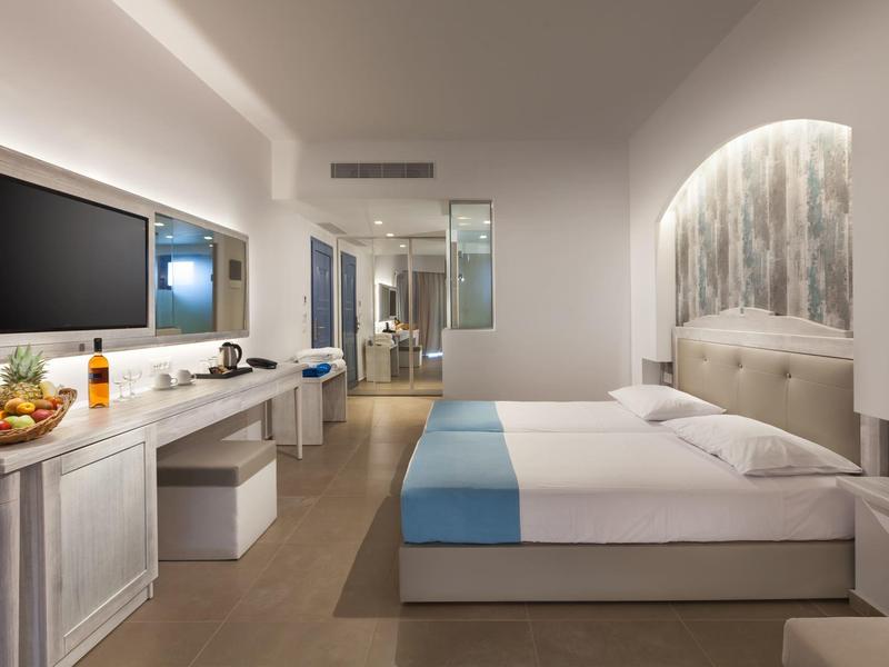 Modernes Hotelzimmer mit Doppelbett, TV, Schreibtisch und stilvoller Beleuchtung.