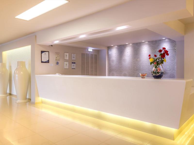 Moderner Hotel-Empfang mit weißer Rezeption und Dekoration aus Vasen und Blumen.