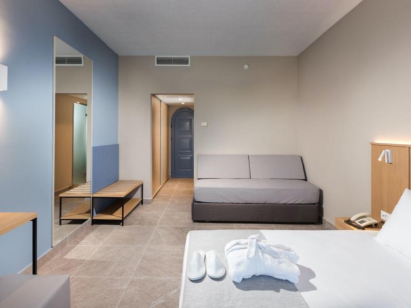 Modern eingerichtetes Hotelzimmer mit Bett, Sofa und kleinem Schreibtisch.