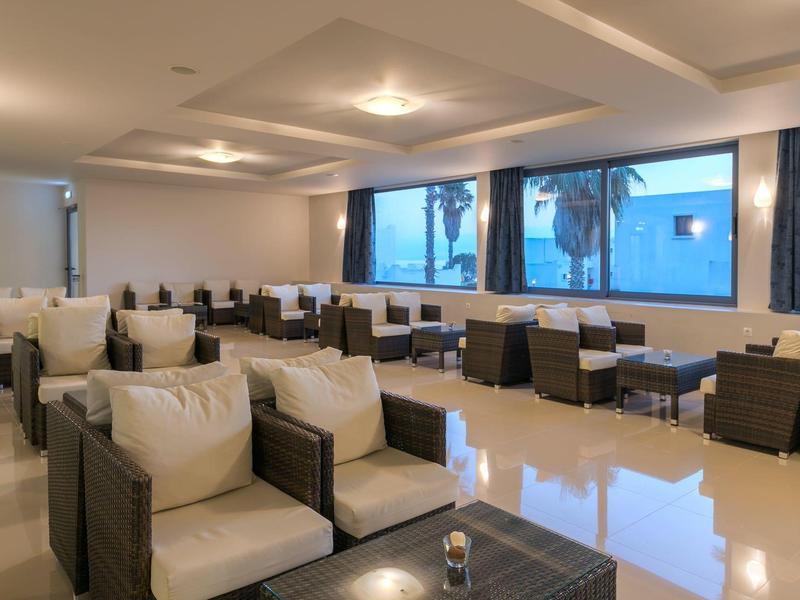 Moderne Lounge mit bequemen Sesseln und großen Fenstern, Blick auf Palmen und Meer.