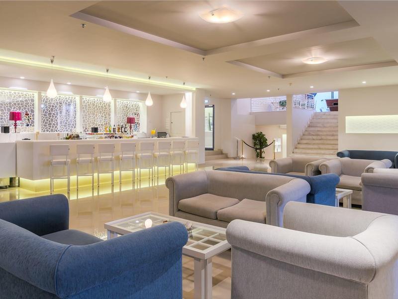 Heller Hotel-Loungebereich mit moderner Bar, bequemen Sofas und weißem, minimalistischem Design.