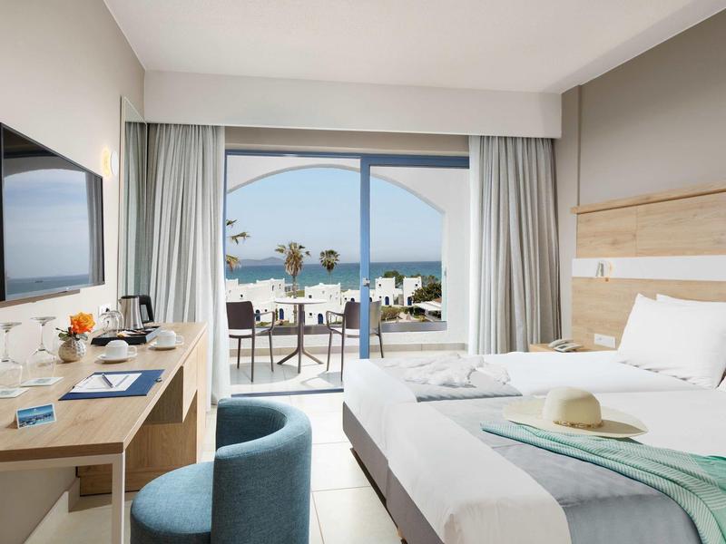 Modernes Hotelzimmer mit Doppelbett, TV, Schreibtisch und Balkon mit Meerblick