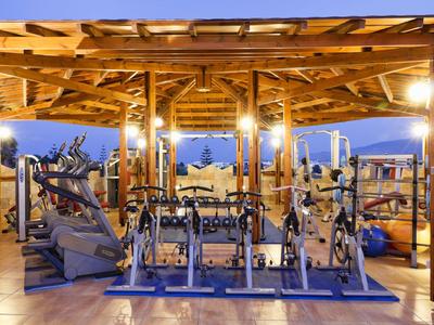 Area palestra all'aperto con pesi e attrezzi cardio sotto struttura di legno al crepuscolo