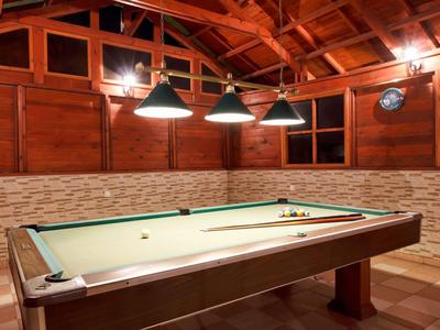 Accogliente sala giochi con un tavolo da biliardo sotto un soffitto di legno e luce calda.