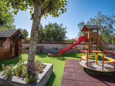 Jasny plac zabaw na zewnątrz z zjeżdżalnią, karuzelą i domkiem zabaw pod czystym niebem.