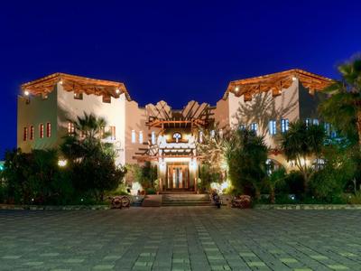 Luksusowy hotel oświetlony nocą z palmami i dekoracyjnym oświetleniem.