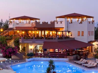 Luksusowy hotel z oświetlonym basenem, leżakami, parasolami i ogrodem o zmierzchu.