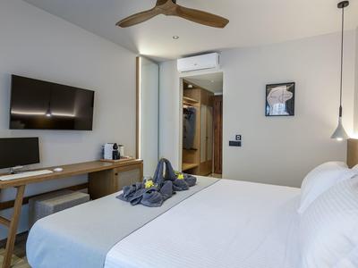 Nowoczesny pokój hotelowy z dużym łóżkiem, biurkiem, telewizorem i garderobą.