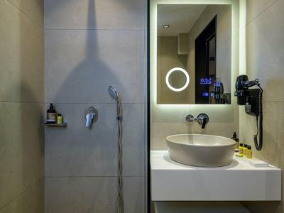 Nowoczesna łazienka z prysznicem bez brodzika, dużym lustrem i umywalką na blacie.