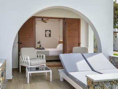 Nowoczesny zewnętrzny salon z podwójnymi leżakami i fotelami przy białym budynku z łukiem.