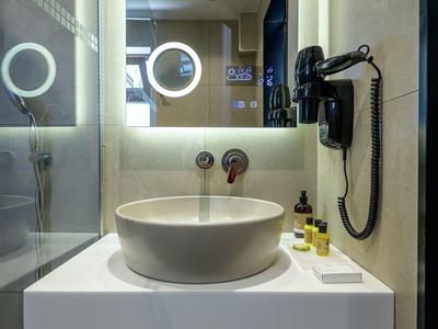 Nowoczesna łazienka hotelowa z podświetlanym lustrem, umywalką nablatową, armaturą ścienną i suszarką do włosów.