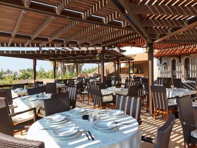 Zewnętrzny taras restauracyjny z drewnianymi meblami pod zacienioną pergolą