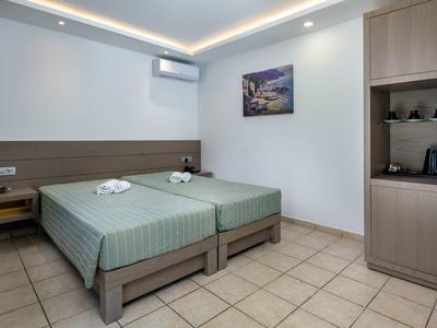 Czysty pokój hotelowy z dwoma pojedynczymi łóżkami, klimatyzacją i stolikami nocnymi.